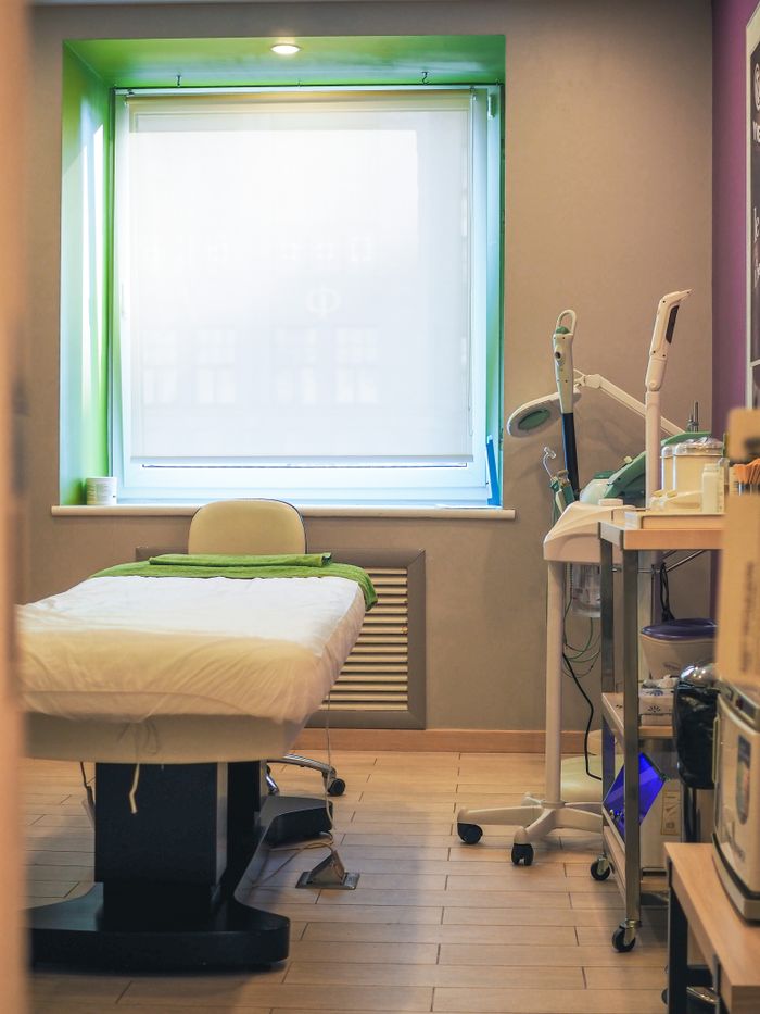 A clean medical room featuring a bed, equipment, and a bright window.